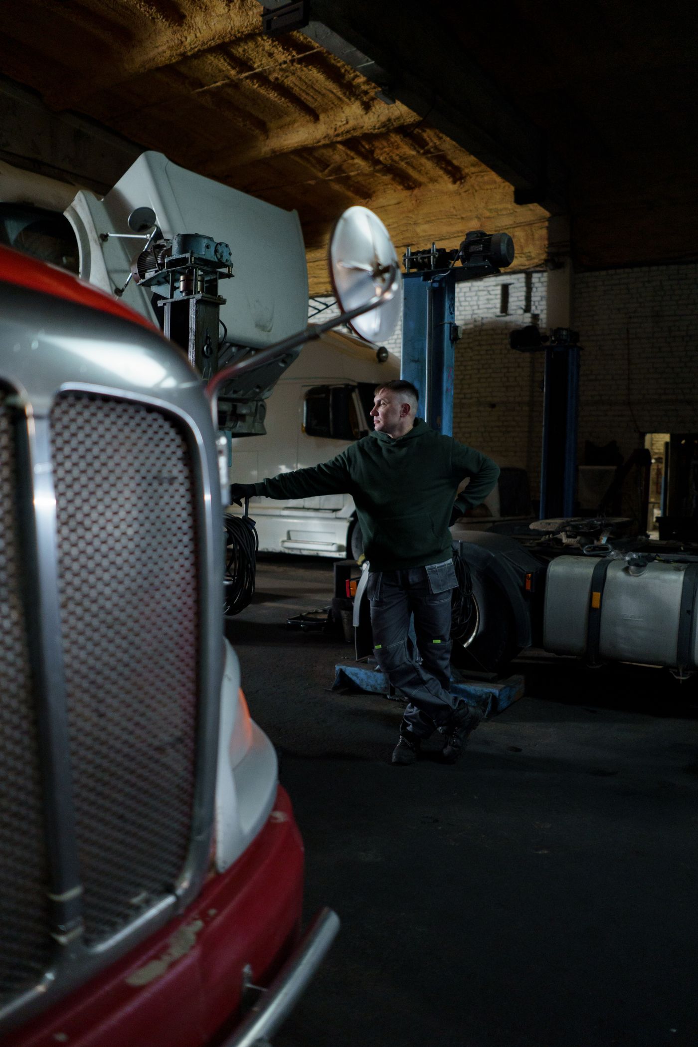 Mechanic working beside a heavy commercial truck in a repair shop