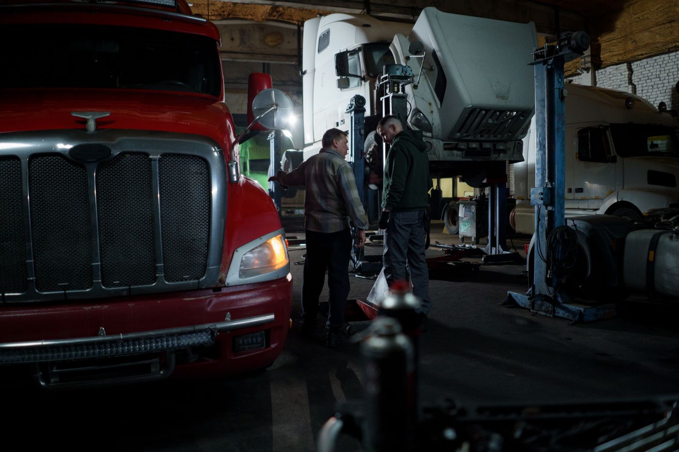 Mechanics inspecting heavy trucks inside a commercial repair bay
