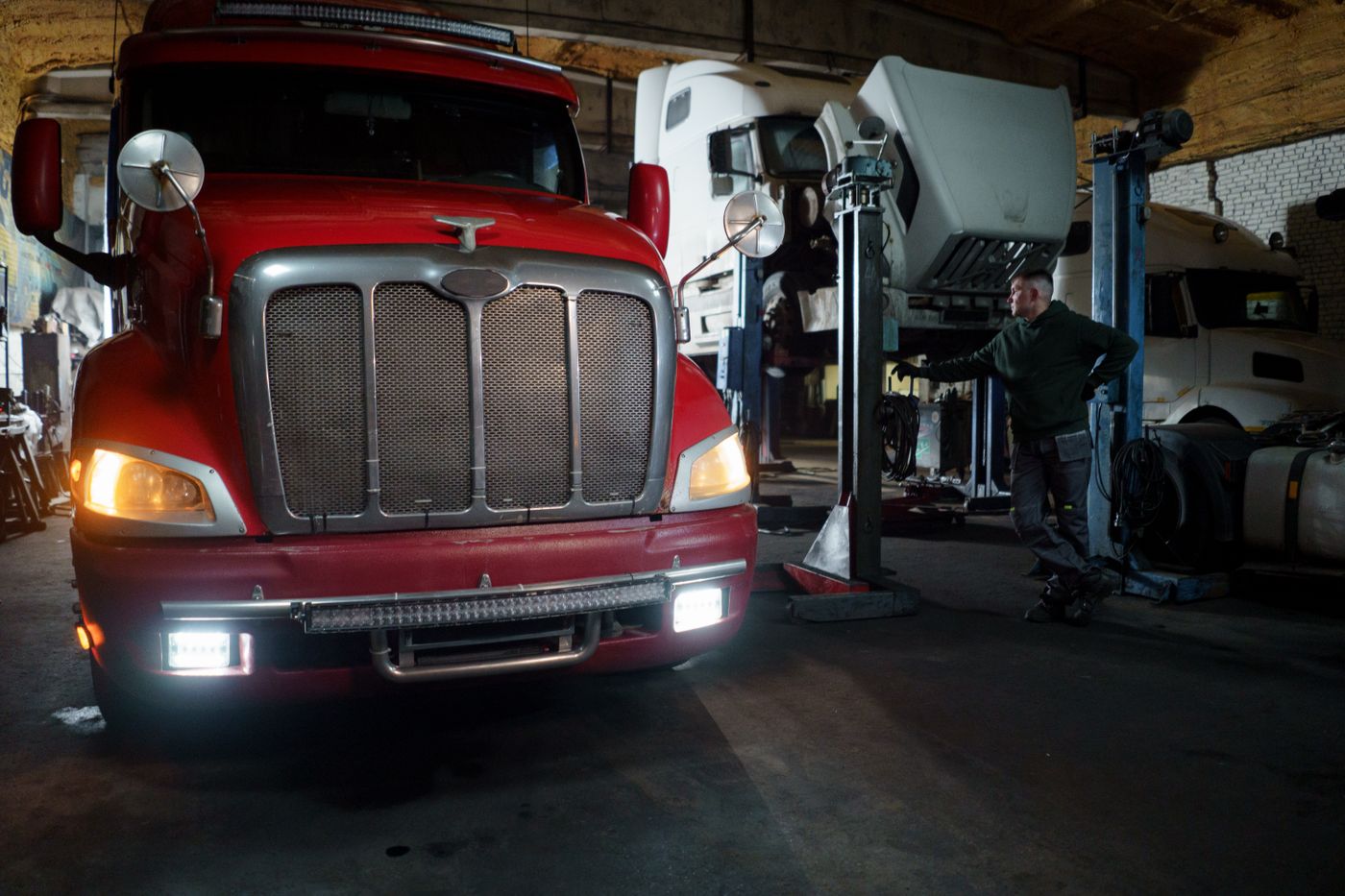 Heavy commercial trucks positioned inside a repair workshop